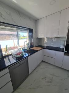 uma cozinha com armários brancos, um lavatório e uma janela em Casa Particular das Pedras em Vila Nova de Gaia
