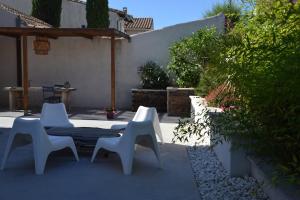 a patio with three white chairs and a bench at Appartement LE BOIS FLOTTE in Saintes-Maries-de-la-Mer