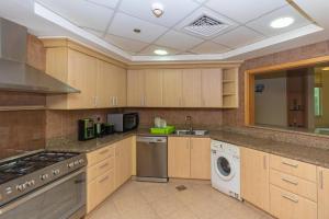 a kitchen with wooden cabinets and a washer and dryer at Spacious 3 Bed Room Apartment - Palm Jumeirah Dubai in Dubai