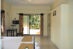 een slaapkamer met een bed en uitzicht op een patio bij Suma beach resort in Dapoli