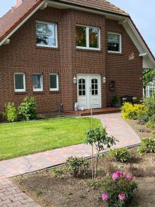 Una casa de ladrillo con un patio con flores y una entrada para autos. en Haus Eierhof, en Papenburg