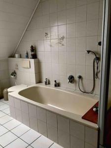a bath tub in a bathroom with white tiles at Haus Eierhof in Papenburg +17 photos