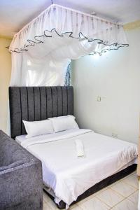 a bed with a canopy in a room with a couch at Unique, Stylish Studio Apartment in Kisumu