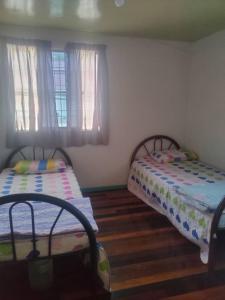 two beds in a room with wooden floors and windows at MAK Homstay upstairs in Kundasang
