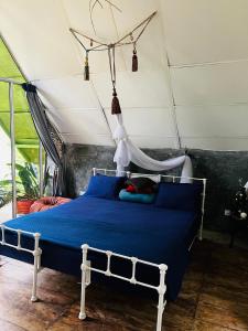a bedroom with a blue bed with a canopy at Moksha eco villa Ella in Ella