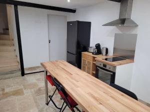 Il comprend une cuisine équipée d'une table en bois et d'un réfrigérateur. dans l'établissement maison des vendangeurs, à Villarzel-Cabardès