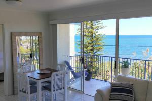Sala de estar con mesa y vistas al océano en Perched above the waves at Kings Beach apartment, en Caloundra