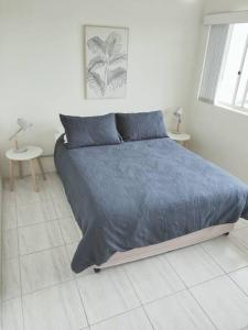 1 dormitorio con 1 cama con manta azul y 2 mesas en Perched above the waves at Kings Beach apartment, en Caloundra