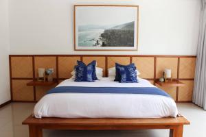 a bedroom with a large bed with blue pillows at Villa Oceana, Candidasa in Candidasa