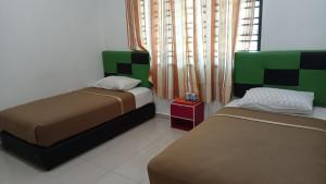 a bedroom with two beds and a window at DLAYARAN VILLA GUEST HOUSE in Kuala Rompin