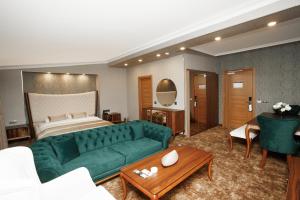 een woonkamer met een groene bank en een bed bij Anemon Uşak Hotel in Usak