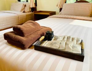 - un plateau avec des serviettes et des livres sur un lit dans l'établissement ViangPhing Resort, à Mae Chan