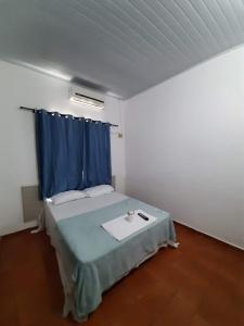 a bedroom with a bed with a blue curtain at OYO Hotel Perola in Cuiabá