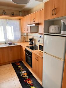 cocina con armarios de madera y nevera blanca en Casa Jerome, en Playa Paraiso