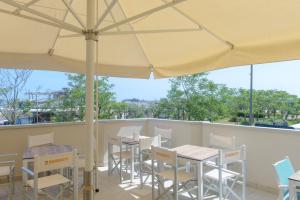 a patio with tables and chairs and an umbrella at Hotel Paloma Beach Front Chiringuitos Time in Rimini