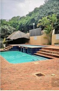 a swimming pool with blue water in front of a building at 84 Camarque Umdloti beach in Umdloti
