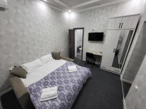um quarto com uma cama, uma secretária e uma televisão em Shahriston GH em Tashkent