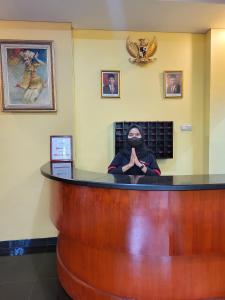 un homme assis au bar dans un salon dans l'établissement RedDoorz Plus near Dunia Fantasi Ancol, à Jakarta