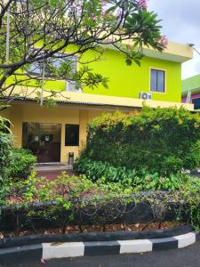 a yellow house with bushes in front of it at RedDoorz Plus near Dunia Fantasi Ancol in Jakarta