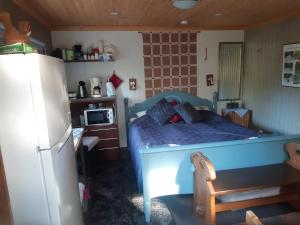 1 dormitorio con 1 cama azul y nevera en Rantakallio Savonlinna, Tervetuloa meille! en Savonlinna
