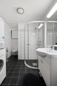 y baño con ducha, lavabo y lavadora. en Frogner House - Forus Leilighetshotell en Stavanger