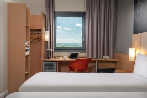 a hotel room with a bed and a desk and a window at ibis Ankara Airport Hotel in Ankara