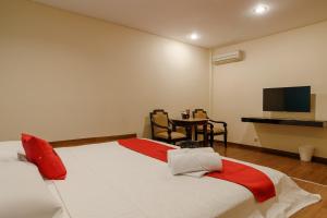 a bedroom with a bed and a table with a television at RedDoorz Plus near Dunia Fantasi Ancol in Jakarta