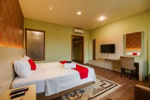 a bedroom with a bed and a desk and a television at RedDoorz Plus near Dunia Fantasi Ancol in Jakarta