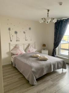 a bedroom with a white bed with dandelions on the wall at Bangų apartamentai in Palanga