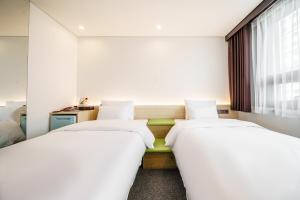 2 Betten in einem Zimmer mit weißen Wänden in der Unterkunft Jamsil Stay Hotel in Seoul