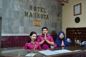 Hotel Mahkota في Pati: مجموعة من ثلاثة أشخاص يجلسون على طاولة للصلاة