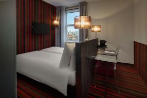 a hotel room with a bed and a desk with a window at WestCord City Centre Hotel in Amsterdam