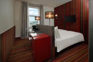 a hotel room with a bed and a desk and a window at WestCord City Centre Hotel in Amsterdam