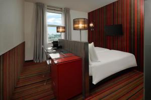 Cette chambre comprend un lit, un bureau et une fenêtre. dans l'établissement WestCord City Centre Hotel, à Amsterdam
