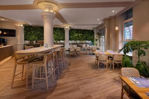 a restaurant with tables and chairs and plants at WestCord City Centre Hotel in Amsterdam