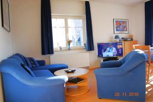 uma sala de estar com duas cadeiras azuis e uma televisão em Feriendomizil-Goethestr-App-12 em Ahlbeck