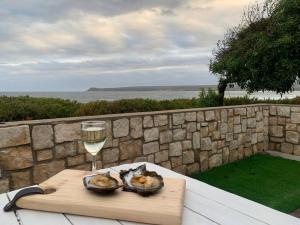 a glass of wine and two bowls of food on a table at Relax in Witsand