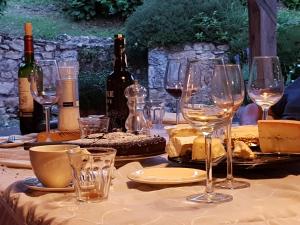 una mesa con copas de vino, queso y botellas de vino en Les Gonies - Amande, en Mauroux