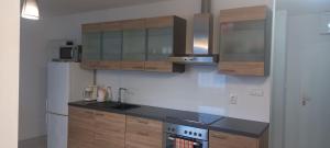 eine Küche mit Holzschränken und einem weißen Kühlschrank in der Unterkunft Apartmán CENTRAL in Banská Bystrica