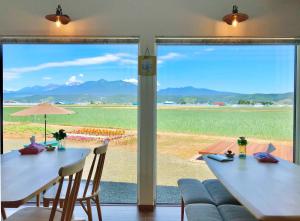 ein Esszimmer mit 2 Tischen und einem großen Fenster in der Unterkunft Shooting Star the Bed & Breakfast in Furano
