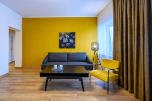 sala de estar con sofá azul y pared amarilla en Kastani Factory Apartments, en Tartu