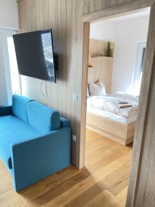 een woonkamer met een blauwe bank en een bed bij Luxury Apartment Monte Carlo in Pörtschach am Wörthersee