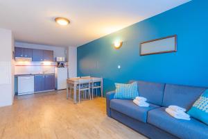 a blue living room with a couch and a kitchen at Appart'City Classic La Roche sur Yon Centre in La Roche-sur-Yon