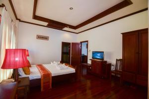 a bedroom with a bed and a lamp and a television at Senesothxuene Hotel in Muang Không