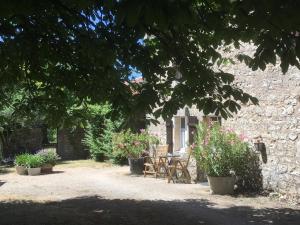 Casa de piedra con mesa, sillas y flores en Les Gonies - Amande, en Mauroux