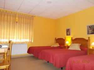 a bedroom with two beds and yellow walls at Hostal Mirador de Avila in Avila