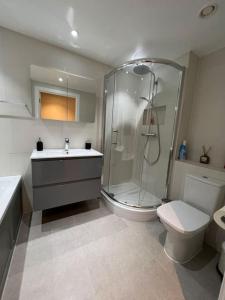 a bathroom with a shower and a toilet and a sink at Modern Stratford Apartment with Parking in London