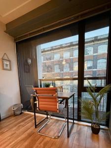 einen Stuhl und einen Tisch in einem Zimmer mit Fenster in der Unterkunft Modern Stratford Apartment with Parking in London