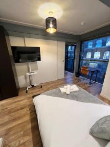 a bedroom with a large white bed and a television at Modern Stratford Apartment with Parking in London