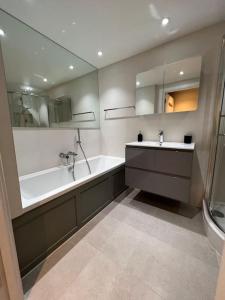 a bathroom with a tub and a sink and a bath tub at Modern Stratford Apartment with Parking in London